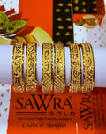 Five ornate gold-plated chain and filigree bangles displayed on a white cylindrical stand, with an orange SAWRA GOLD brand box visible underneath.