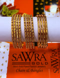 A set of gold-plated bangles displayed on a white cylindrical stand, with SAWRA GOLD branding visible on the packaging below.