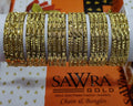 Gold bangles on a white roll with Sawra Gold branding in the background