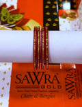 Five red bangles with gold foil patterns wrapped around a white cylindrical display stand, with SAWRA GOLD branding visible in the background packaging.