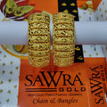 Gold bangles on a Sawra Gold branded stand with packaging in the background