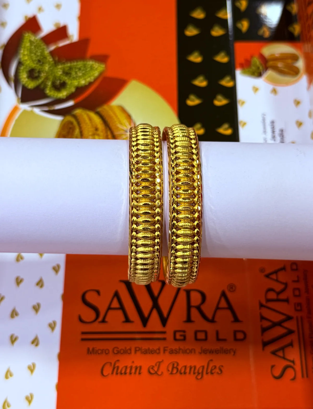 Gold bangles on a Sawra Gold branded box with a blurred background